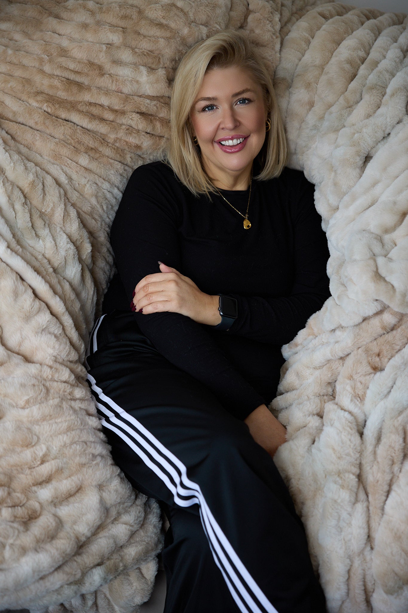 Woman in black outfit with white stripes sitting on a textured beige blanket
