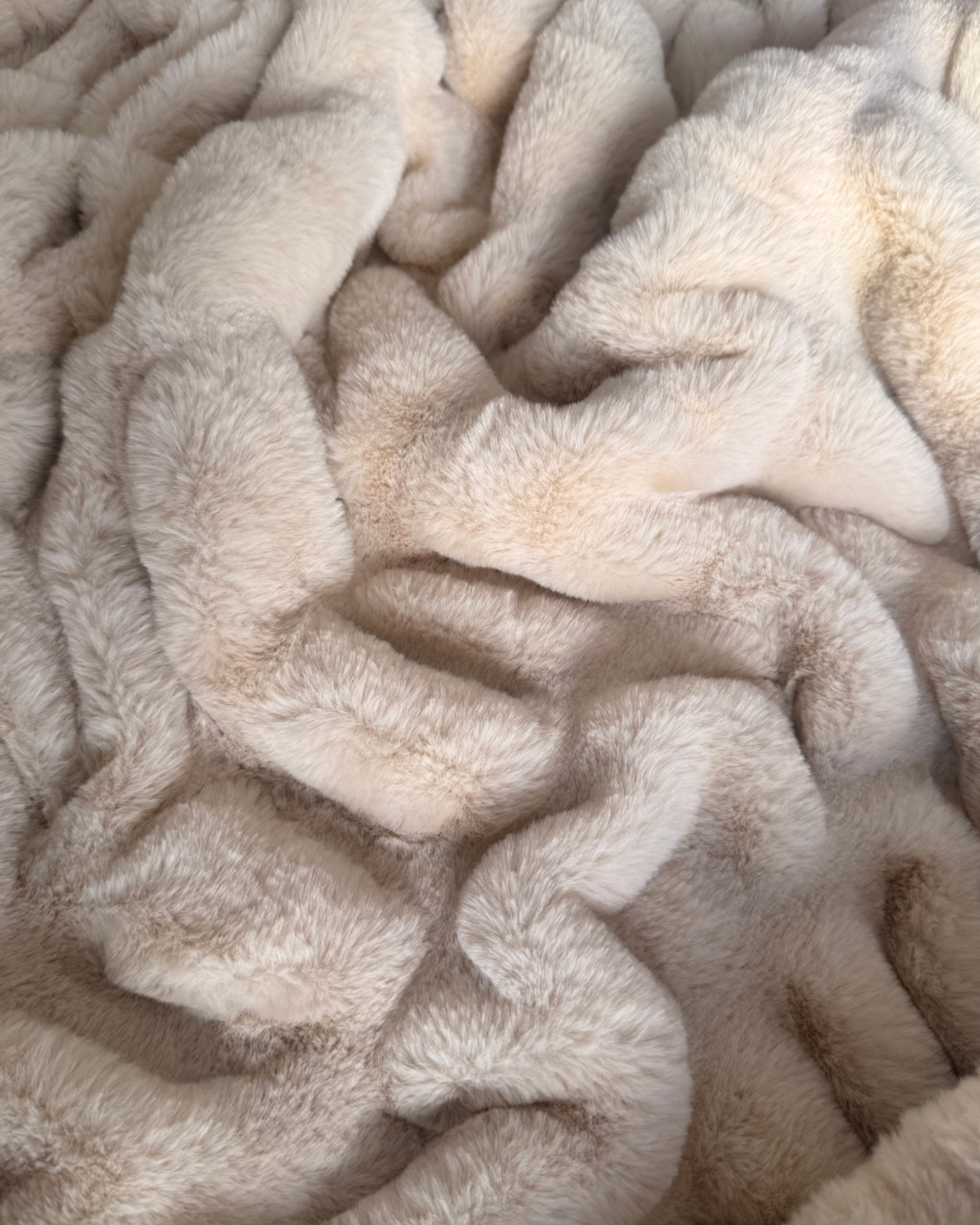 Close up of a faux fur beige blanket.