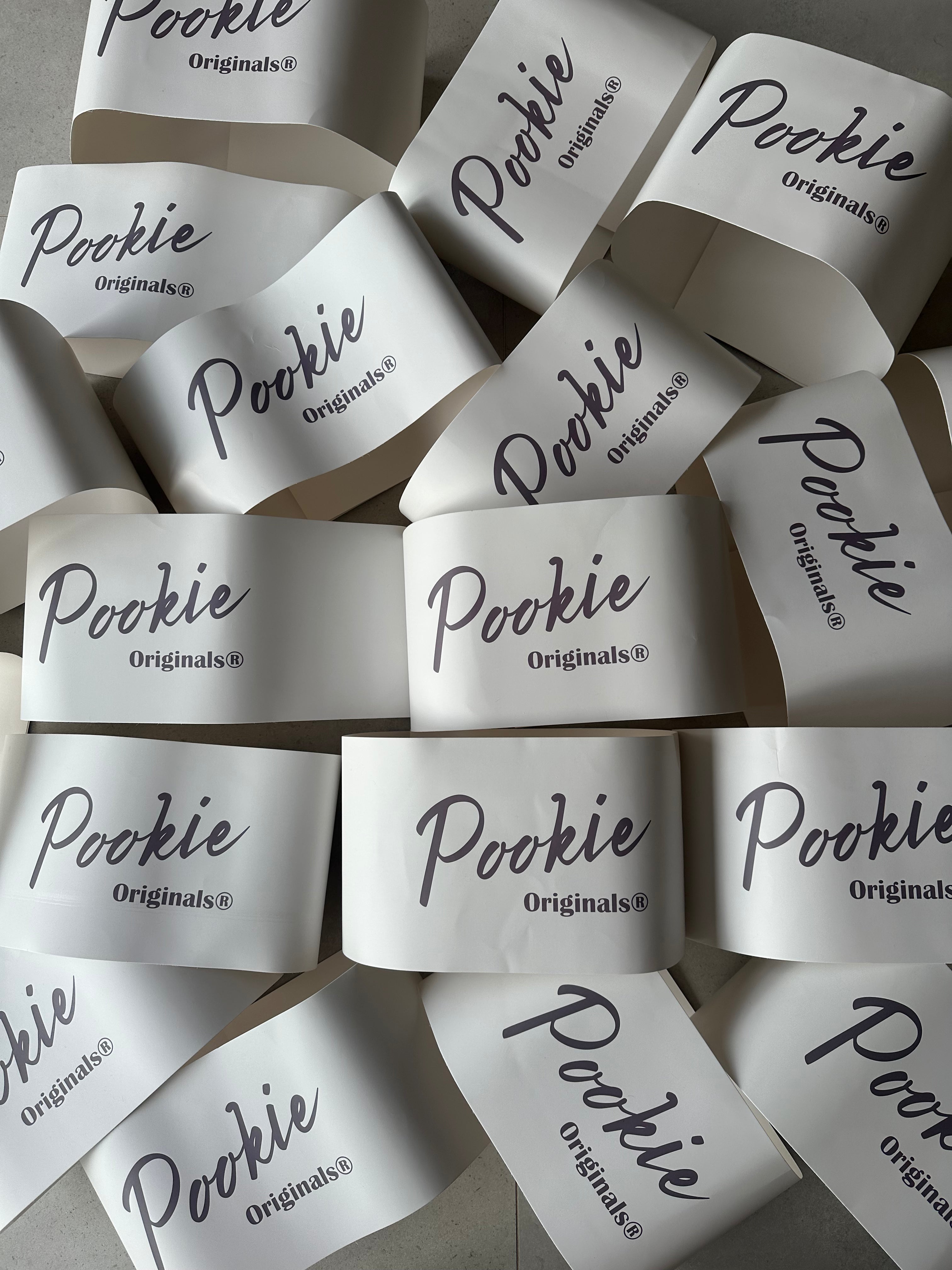 Multiple 'Pookie Originals' labels scattered on a light background